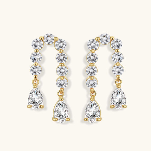 Gold-plated earrings with vertical line of clear crystals and teardrop pendants on neutral background